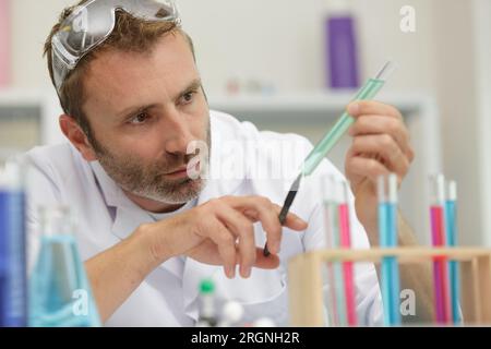 Konzentrierter männlicher Forscher, der ein Reagenzglas hält Stockfoto