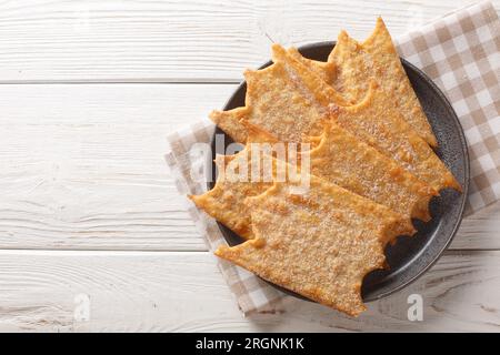 Knusprige französische Festtagsfritters Oreillette Nahaufnahme auf einem Teller auf dem Tisch. Horizontale Draufsicht von oben Stockfoto