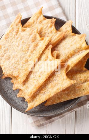 Oreillettes aus der Provence, Mardi Gras, Fritters, die auf dem Teller auf dem Holztisch verstaut werden. Vertikale Draufsicht von oben Stockfoto