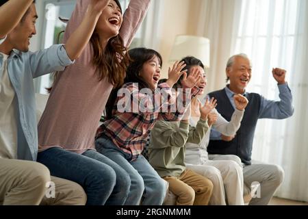 Eine asiatische Familie der 3. Generation, die zu Hause zusammen Fußball-tv-Übertragungen ansieht Stockfoto