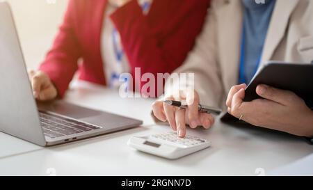 Nahaufnahme von zwei Buchhaltern, die gemeinsam an einem Finanzprojekt arbeiten, Umsatz und Ausgaben mit einem Rechner berechnen und das Budget planen. Stockfoto