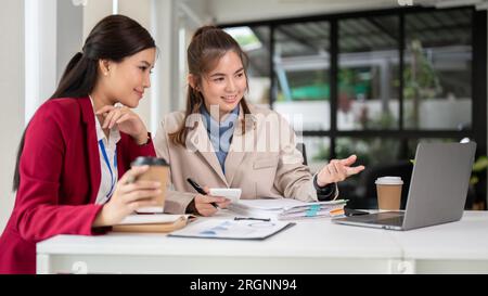 Eine professionelle asiatische Finanzanalytikerin präsentiert ihr Projekt auf ihrem Laptop und berät ihren Chef bei der Besprechung zu Finanzinvestitionen Stockfoto