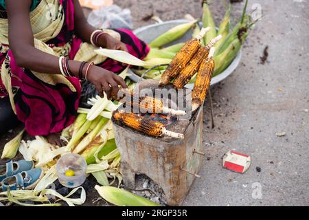 Eine nicht identifizierbare, arme indische Frau, die gebratenen Mais in einem Straßenladen verkauft Stockfoto