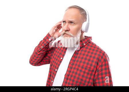 Mittelalter Betrieb. 60er Jahre älterer Mann mit grauem Bart und Schnurrbart mit kabellosen Kopfhörern Stockfoto