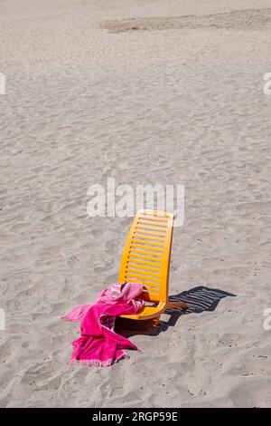 Gelbe Liege und Handtuch isoliert am Strand Sand Stockfoto