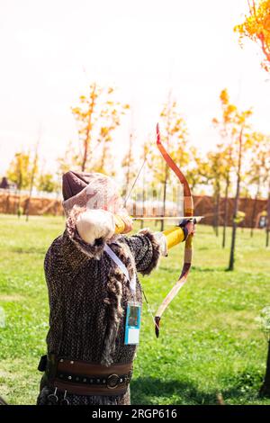 Bogenschütze in traditioneller Kleidung, die einen Pfeil schießt Stockfoto