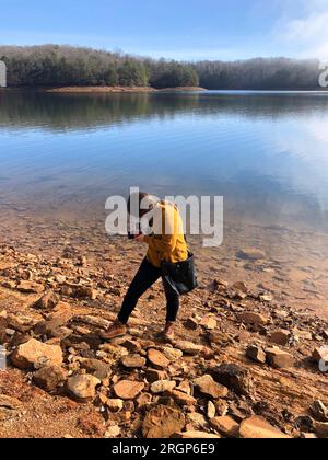 Frauenfotos fallen mit ihrer mittelgroßen Filmkamera auf den See Stockfoto