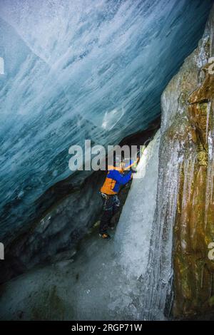 Abenteurer erkunden und Eisklettern unter dem Gletscher in einer Höhle Stockfoto