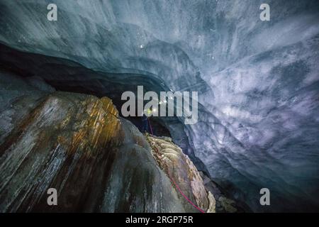 Blick aus dem niedrigen Winkel auf einen Eiskletterer, der einen gefrorenen Wasserfall hinunterrappelt Stockfoto
