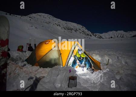 Skifahrer kochen nachts im Zelt in den Bergen. Stockfoto