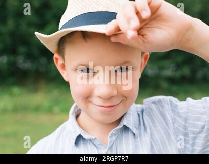 Porträt eines Jungen, der frech aussieht und einen Sommerhut trägt Stockfoto