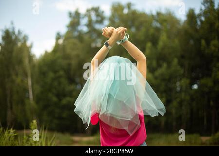 Leichtes Material im Sommer. Mädchen im Park. Hände hoch. Stockfoto