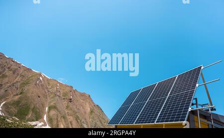 Solarpaneele sind an der Fassade eines Hauses in den Bergen installiert. Sonniger Tag Stockfoto
