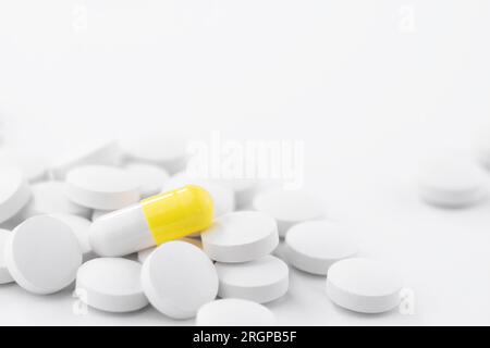 Gelb und weiß pharmazeutische medizinische Pillen, Kapseln, Tabletten auf einem weißen Tisch. Konzept von Medizin und Gesundheitswesen Stockfoto