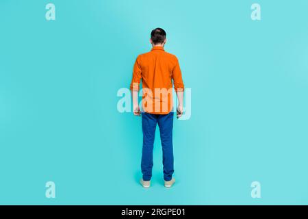 Ganzkörperfoto eines Geschäftsmannes Alterspensionär trägt orangefarbenes Hemd Denimjeans Freizeitkleidung isoliert auf cyanfarbenem Hintergrund Stockfoto