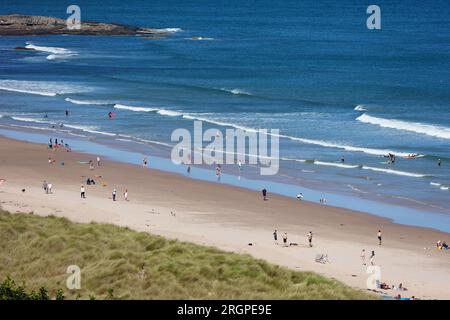 Bamburgh, Northumberland, Großbritannien. 11. August 2023. UK Weather: Ein heller und sonniger Tag am Strand von Bamburgh, an dem Besucher und Surfer die Sonne genießen. Bildnachweis: PAL News/Alamy Live News Stockfoto