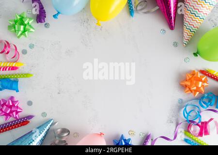 Geburtstagsparty flach liegender Kompositionsrahmen. Bunte Ballons, Kuchenkerzen, Kegelhüte, Schleifen, Bänder. Einladungskonzept mit Kopierbereich. Stockfoto