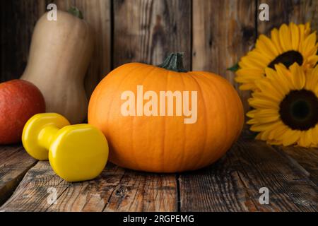 Herbstliche Kürbisse, Hantel, Sonnenblumen. Gesunde Fitness Herbstkomposition für Halloween oder Thanksgiving. Fitness-Training und Sporttrainingskonzept. Stockfoto