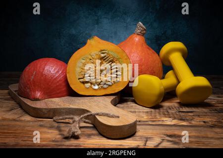 Hokkaido Red kuri Kürbis Kürbisse und Kurzhanteln. Gesunde Fitness Herbst, Fitness Workout, Sport Training Herbstzusammensetzung für Halloween, Thanksgiving. Stockfoto