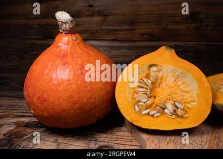 Hokkaido-Kürbisse auf hölzernem Hintergrund. Roter kuri-Kürbis Herbst rustikale Komposition für Halloween oder Thanksgiving. Stockfoto