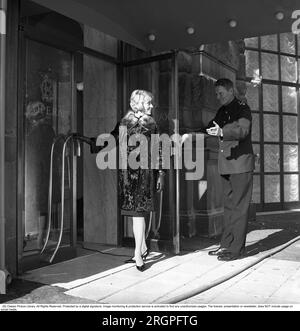 Service in den 1960er. Eine junge, modische Frau steht vor der Tür des Restaurants Operakällaren in Stockholm, mit einem Portier, der die Tür galant hochhält. Schweden 1962. Kristoffersson Ref. CV87-5 Stockfoto