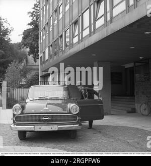In den 1960er Jahren. Ein Mann steht vor seinem Auto, einem Opel Kapitän, vor einem Hochhaus. Er ist angezogen wie ein Geschäftsmann in Anzug und Hut. Schweden 1962. Kristoffersson Ref. CV9-11 Stockfoto