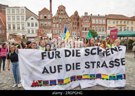 11. August 2023, Niedersachsen, Lüneburg: Teilnehmer eines protestmarsches der Klimabewegung Fridays for Future tragen ein Banner mit der Aufschrift „for Rail on the Road“. Die Demonstration durch Lüneburg soll unter anderem die Aufmerksamkeit auf die Notwendigkeit der neuen Eisenbahnstrecke Hamburg-Hannover lenken. Foto: Georg Wendt/dpa Stockfoto