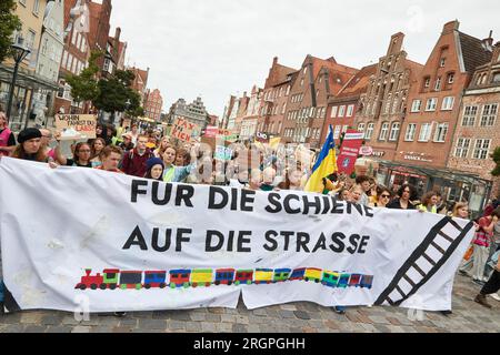 11. August 2023, Niedersachsen, Lüneburg: Teilnehmer eines protestmarsches der Klimabewegung Fridays for Future tragen ein Banner mit der Aufschrift „for Rail on the Road“. Die Demonstration durch Lüneburg soll unter anderem die Aufmerksamkeit auf die Notwendigkeit der neuen Eisenbahnstrecke Hamburg-Hannover lenken. Foto: Georg Wendt/dpa Stockfoto