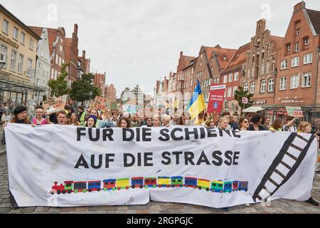 11. August 2023, Niedersachsen, Lüneburg: Teilnehmer eines protestmarsches der Klimabewegung Fridays for Future tragen ein Banner mit der Aufschrift „for Rail on the Road“. Die Demonstration durch Lüneburg soll unter anderem die Aufmerksamkeit auf die Notwendigkeit der neuen Eisenbahnstrecke Hamburg-Hannover lenken. Foto: Georg Wendt/dpa Stockfoto