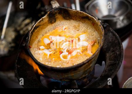 Tintenfische mit rotem Curry an einem Street Food Stand in Bangkok, Thailand. Stockfoto