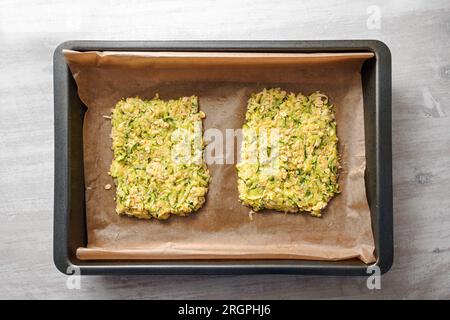 Zucchini- und Haferflocken-Teig als Basis für vegane kohlenhydratarme Pizza oder Gemüsekuchen auf einem Tablett mit Backpapier, hohe Sicht von oben, ausgewählt Stockfoto