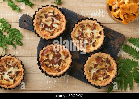 Herzhafter Handkuchen mit Pfifferlingpilzen, Sahne und Käse auf dem Schneidebrett auf rustikalem, altem, weißem Holztisch. Hausgemachte Torten mit Saison Stockfoto