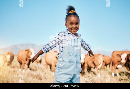 Farm, Kühe und Porträt eines Mädchen mit offenen Armen für Ökologie, Abenteuer und Landwirtschaft im Feld. Landleben, nachhaltige Landwirtschaft und glückliches afrikanisches Kind Stockfoto