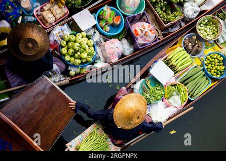 Frauen, die Gemüse und Obst aus ihren Kanus auf dem schwimmenden Tha Kha-Markt in Thailand verkaufen. Stockfoto