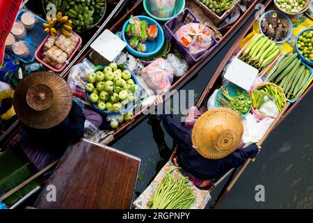 Frauen, die Gemüse und Obst aus ihren Kanus auf dem schwimmenden Tha Kha-Markt in Thailand verkaufen. Stockfoto