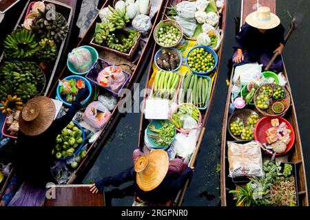 Frauen, die Gemüse und Obst aus ihren Kanus auf dem schwimmenden Tha Kha-Markt in Thailand verkaufen. Stockfoto