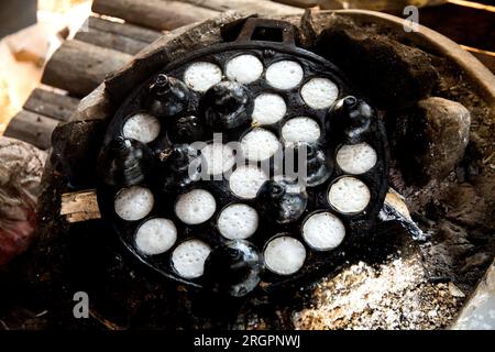 Frau bereitet Kokosnuss-thai-Desserts zu. Kanom krok ist ein leckeres thailändisches Mini-Pfannkuchen auf Kokosnussmilchbasis, das ebenfalls beliebt ist. Stockfoto