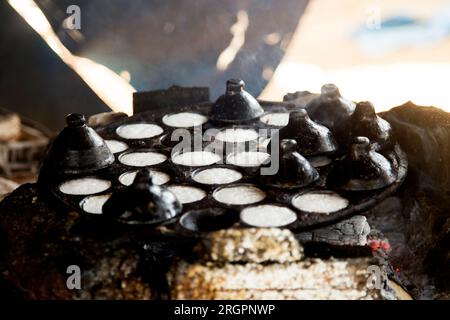 Frau bereitet Kokosnuss-thai-Desserts zu. Kanom krok ist ein leckeres thailändisches Mini-Pfannkuchen auf Kokosnussmilchbasis, das ebenfalls beliebt ist. Stockfoto