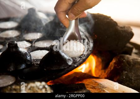 Frau bereitet Kokosnuss-thai-Desserts zu. Kanom krok ist ein leckeres thailändisches Mini-Pfannkuchen auf Kokosnussmilchbasis, das ebenfalls beliebt ist. Stockfoto