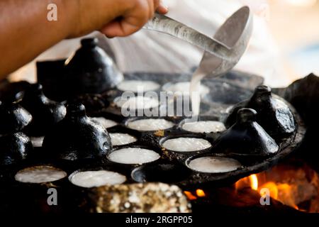 Frau bereitet Kokosnuss-thai-Desserts zu. Kanom krok ist ein leckeres thailändisches Mini-Pfannkuchen auf Kokosnussmilchbasis, das ebenfalls beliebt ist. Stockfoto