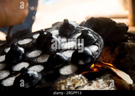 Frau bereitet Kokosnuss-thai-Desserts zu. Kanom krok ist ein leckeres thailändisches Mini-Pfannkuchen auf Kokosnussmilchbasis, das ebenfalls beliebt ist. Stockfoto