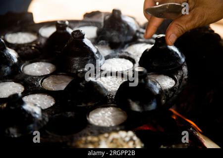 Frau bereitet Kokosnuss-thai-Desserts zu. Kanom krok ist ein leckeres thailändisches Mini-Pfannkuchen auf Kokosnussmilchbasis, das ebenfalls beliebt ist. Stockfoto