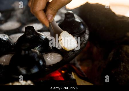 Frau bereitet Kokosnuss-thai-Desserts zu. Kanom krok ist ein leckeres thailändisches Mini-Pfannkuchen auf Kokosnussmilchbasis, das ebenfalls beliebt ist. Stockfoto