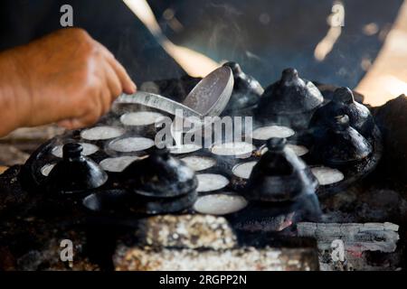 Frau bereitet Kokosnuss-thai-Desserts zu. Kanom krok ist ein leckeres thailändisches Mini-Pfannkuchen auf Kokosnussmilchbasis, das ebenfalls beliebt ist. Stockfoto