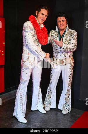 Berlin, Deutschland. 11. Aug. 2023. Der Elvis-Künstler Grahame Patrick (r) aus der Serie „Stars in Concert“ steht neben einer frisch restaurierten Elvis-Figur im Madame Tussauds Berlin Wachsfigurenkabinett. Bis jetzt wurde die Figur in der Uniform der US-Armee dargestellt, wie sie der Sänger 1958 während seines Militärdienstes in Westdeutschland trug. Nach 15 Jahren im Dienst des Wachsmuseums hat Elvis in den letzten Monaten ein neues Outfit und eine neue Frisur erhalten. Kredit: Soeren Stache/dpa/Alamy Live News Stockfoto