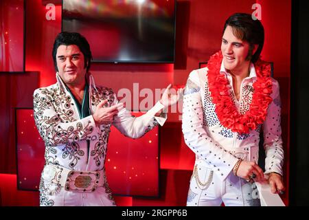 Berlin, Deutschland. 11. Aug. 2023. Der Elvis-Künstler Grahame Patrick (l) aus der Serie „Stars in Concert“ steht neben einer frisch restaurierten Elvis-Figur im Madame Tussauds Berlin Wachsfigurenkabinett. Bis jetzt wurde die Figur in der Uniform der US-Armee dargestellt, wie sie der Sänger 1958 während seines Militärdienstes in Westdeutschland trug. Nach 15 Jahren im Dienst des Wachsmuseums hat Elvis in den letzten Monaten ein neues Outfit und eine neue Frisur erhalten. Kredit: Soeren Stache/dpa/Alamy Live News Stockfoto