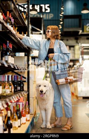 Eine Frau besucht mit ihrem Hund einen Weinladen Stockfoto