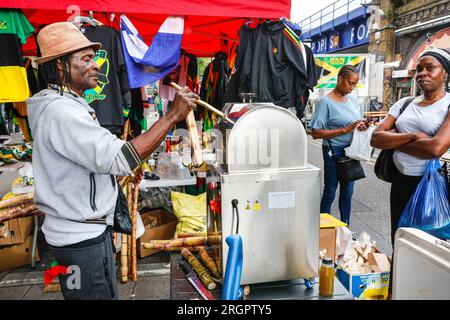 Verkäufer, der frischen Zuckerrohrsaft herstellt, Brixton Station Road Market, Brixton, South London, England Stockfoto