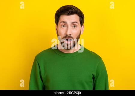 Foto eines erstaunten, beeindruckenden Mannes in grüner Kleidung. Wow, saisonales Sonderangebot am Schwarzen freitag, isoliert auf gelbem Hintergrund Stockfoto