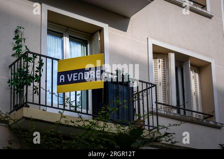 „Ein Vendre“ in französischer Sprache auf einem gelben Schild, das an der Außenseite einer Wohnung in einem Wohngebäude angebracht ist. Konzept des Immobilienmarktes in Frankreich Stockfoto